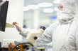 Photo: Scientist in clean suit working at computer in silicon wafer manufacturing laboratory Scientist in clean suit working at computer in silicon wafer manufacturing laboratory