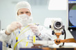 Photo: Scientist in clean suit adjusting wires on machine in silicon wafer manufacturing laboratory Scientist in clean suit adjusting wires on machine in silicon wafer manufacturing laboratory
