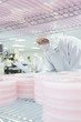 Photo: Scientist in clean suit checking batches of silicon wafers in laboratory Scientist in clean suit checking batches of silicon wafers in laboratory