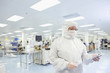 Photo: Scientist in clean suit looking down at clipboard in silicon wafer manufacturing laboratory Scientist in clean suit looking down at clipboard in silicon wafer manufacturing laboratory