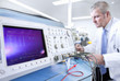 Engineer working at electrical test bench next to oscilloscope