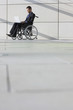 Businessman in wheelchair using laptop in lobby