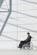 Businessman in wheelchair using laptop in lobby