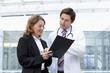 Businesswoman and doctor reviewing paperwork in hospital