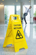 Businessman slipping behind wet floor sign in lobby