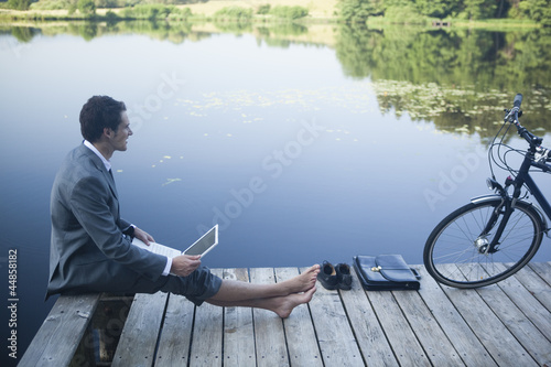 Photo: Young businessman using laptop near lake Young businessman using laptop near lake
