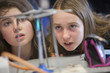 Close up of girls experimenting with Bunsen burner in science class