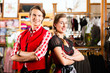Paar probiert Dirndl und Lederhose in Boutique 