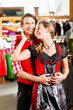 Paar probiert Dirndl und Lederhose in Boutique