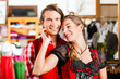 Paar probiert Dirndl und Lederhose in Boutique 