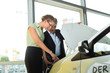 man and woman in car dealership looking under  a hood
