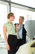 man and woman in car dealership looking under  a hood