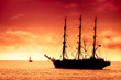 Tall ship sailing in red sunset