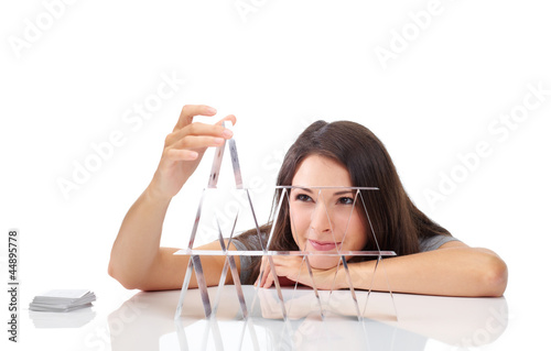 Photo: Young woman is building a house of cards Young woman is building a house of cards