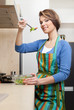 Attractive woman in striped apron cooks vegetables 