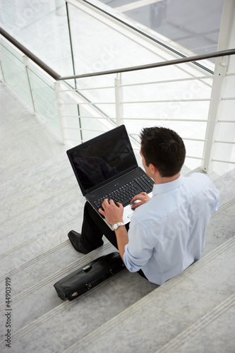 Photo: Businessman sitting on some steps with a laptop Businessman sitting on some steps with a laptop