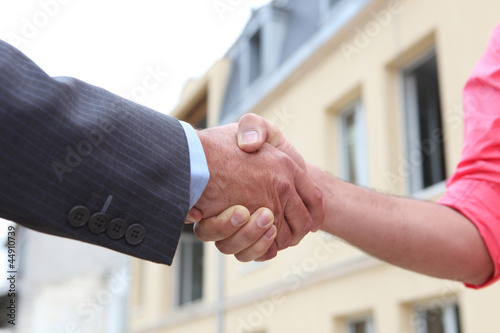 Photo: Couple shaking hands outside a house Couple shaking hands outside a house