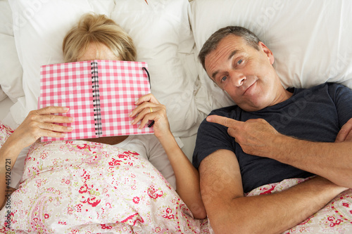 Photo: Bored Looking Senior Man Lying In Bed Next To Senior Woman Readi Bored Looking Senior Man Lying In Bed Next To Senior Woman Readi