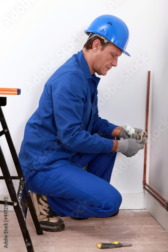 Photo: Construction worker installing a pipe Construction worker installing a pipe