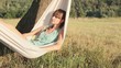Pretty young girl swinging on hammock at sunset