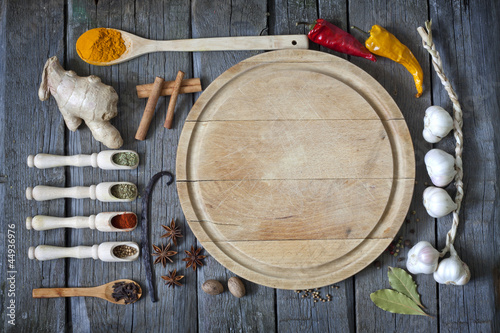 Photo: Exotic spices and empty cutting board food background Exotic spices and empty cutting board food background