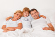 Familie liegt am Morgen im Bett