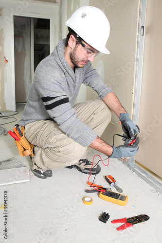 Photo: Man snipping wall wiring Man snipping wall wiring