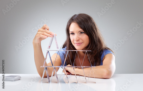 Photo: Young woman is making a house of cards 2 Young woman is making a house of cards 2