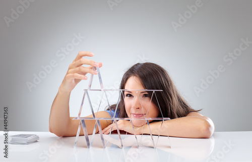 Photo: Young woman is making a house of cards 1 Young woman is making a house of cards 1