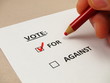 Voting 'yes' on a paper ballot with a red pencil