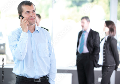 Photo: A young handsome business man on phone at office building A young handsome business man on phone at office building