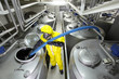 technician in uniform filling large  silver tank in factory