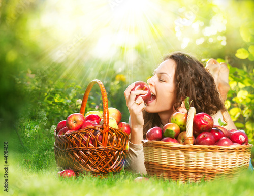 Photo: Beautiful Girl Eating Organic Apple in the Orchard Beautiful Girl Eating Organic Apple in the Orchard