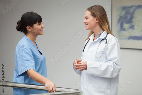 Photo: Nurse talking and smiling with female doctor Nurse talking and smiling with female doctor