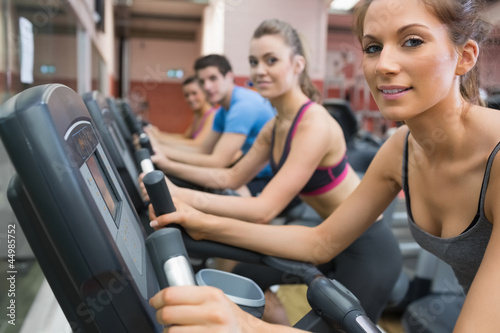 Photo: Four people smiling and riding on an exercise bike Four people smiling and riding on an exercise bike