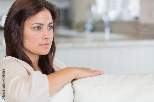 Photo: Woman on sofa looking thoughtful Woman on sofa looking thoughtful