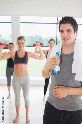 Photo: Man standing at the gym holding a bottle of water Man standing at the gym holding a bottle of water