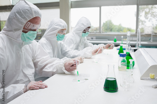 Photo: Three chemists working in protective suits Three chemists working in protective suits
