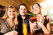 Young people drinking cocktails in bar or restaurant
