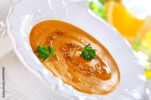 Photo: Pumpkin soup with orange juice in white plate, soft focus. Pumpkin soup with orange juice in white plate, soft focus.
