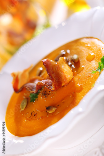 Photo: Pumpkin soup with orange juice in white plate, soft focus. Pumpkin soup with orange juice in white plate, soft focus.