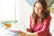 Young smiling woman is drinking coffee in a cafe