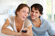 Couple sitting in sofa with remote control in hands