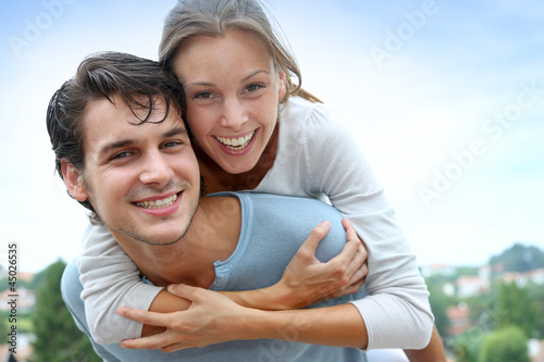 Photo: Man giving piggyback ride to girlfriend outside Man giving piggyback ride to girlfriend outside