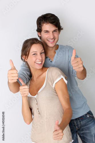 Photo: Cheerful couple showing thumbs up, isolated Cheerful couple showing thumbs up, isolated