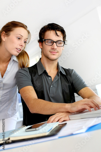 Photo: Co-workers in office discussing project Co-workers in office discussing project