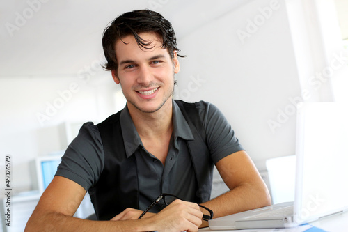 Photo: Portrait of young man working in office Portrait of young man working in office