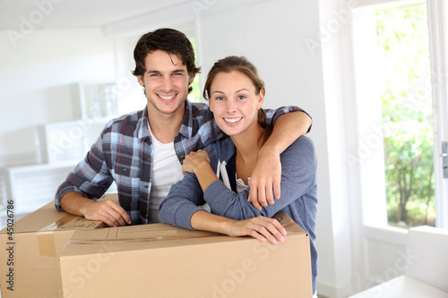 Photo: Smiling couple leaning on boxes in new home Smiling couple leaning on boxes in new home