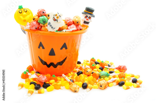 Photo: Jack-o-lantern candy pail with a pile of Halloween candy Jack-o-lantern candy pail with a pile of Halloween candy