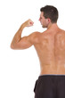 Strong sports man showing biceps. Rear view